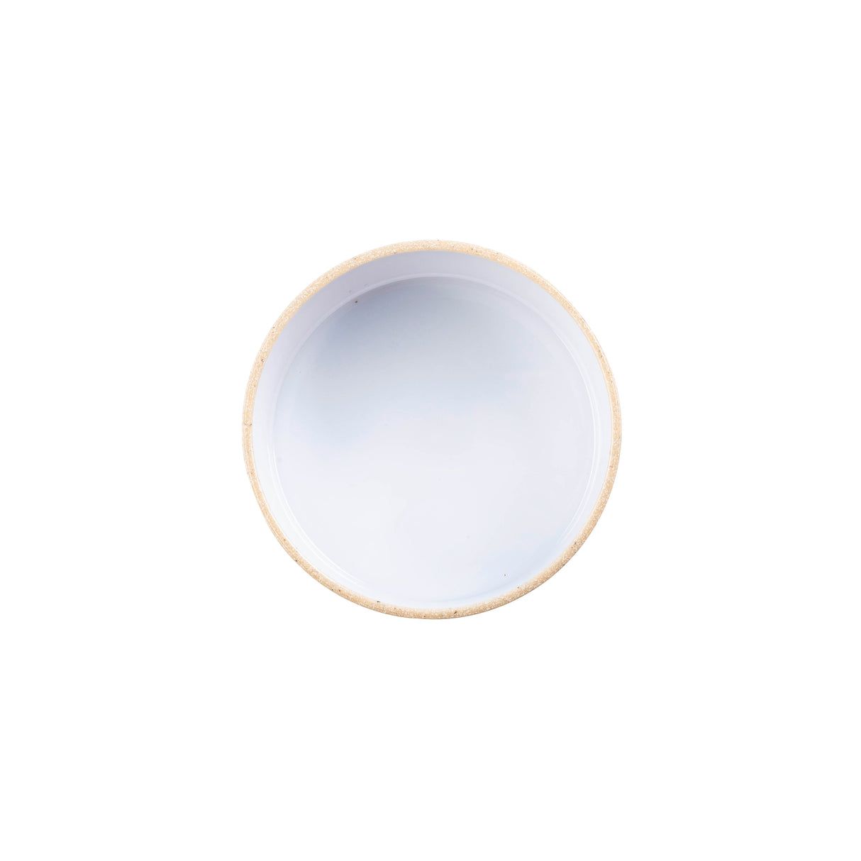 A round, beige-rimmed ceramic bowl filled with a smooth, opaque white liquid sits centered on a plain white background. The bowl is stackable and dishwasher safe, making it as practical as it is elegant.