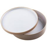 A round, shallow beige bowl with a white interior is shown with its matching lid slightly askew, revealing the inside. The stackable bowl and lid have smooth edges and a minimalist design, photographed against a plain white background.