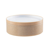 A round, shallow styrene plastic bowl with a tan cork-like textured exterior and a smooth white interior. The bowl has straight sides, an open top, and a minimalist, modern appearance. The background is plain white.