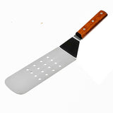 A stainless steel turner with a rectangular, perforated blade and a wood handle secured by three metal rivets, lies on a white background. The blade has rounded edges and ten small circular holes arranged in rows.