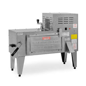 A commercial beignet fryer made of stainless steel with a boxy shape, labeled Olde New Orleans, stands on four legs beside a high volume ice shaver. It features a front-loading door, heat vents, control knobs, and instructional stickers on the side.