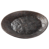 A round, shallow Lunara Collection Plate with a rustic, hammered texture and an uneven, wavy rim. Its mottled brown and black stone pattern finish gives it an earthy, handcrafted look. The background is white.