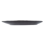 A low, round Lunara Collection Plate in black ceramic is seen from the side against a white background; the plate features a slightly irregular, handcrafted edge and a flat, gently sloping profile.