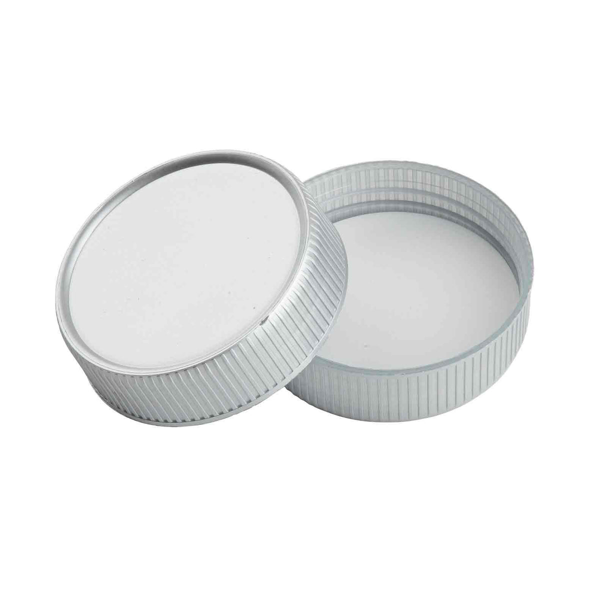 Two round, silver-colored replacement lids are shown. One lid lies flat with the open side facing up, while the other leans against it, displaying its smooth white inner surface and grooved texture on the outer edge.