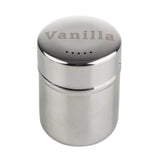 A shiny stainless steel shaker with the word Vanilla engraved on the lid. The lid has small holes in the center for sprinkling contents. This reflective, cylindrical shaker is dishwasher safe and commonly used for dispensing powdered ingredients.