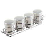 Four small stainless steel canisters with labeled lids (Vanilla, Cocoa, Nutmeg, Cinnamon) and side clasps sit neatly in a chrome-plated rack. This stylish shaker set keeps your spices organized and easily accessible.
