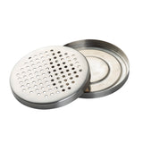 A round TableCraft stainless steel soap dish with two parts: a perforated, flat drip tray top for drainage and a shallow solid base. Both feature smooth, polished finishes and fit together neatly. The dish is placed on a white background.