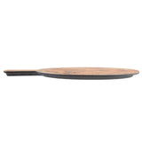 A flat, round olive wood serving paddle with a short handle is shown from the side against a white background. Its rich wood grain top contrasts beautifully with the darker edges and handle.