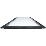 A rectangular glass panel with a black metal frame, part of Empura Refrigeration, is shown horizontally laid flat. The image is taken from a low angle by one short edge, highlighting the sturdy frame and small metal brackets at each front corner.