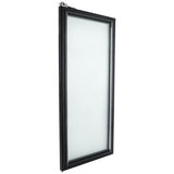 A photo of a rectangular, vertically oriented glass door with a black frame, similar to those found on Empura Refrigeration units. The frosted or opaque pane obscures visibility, and the angle highlights the frame’s thickness and depth.