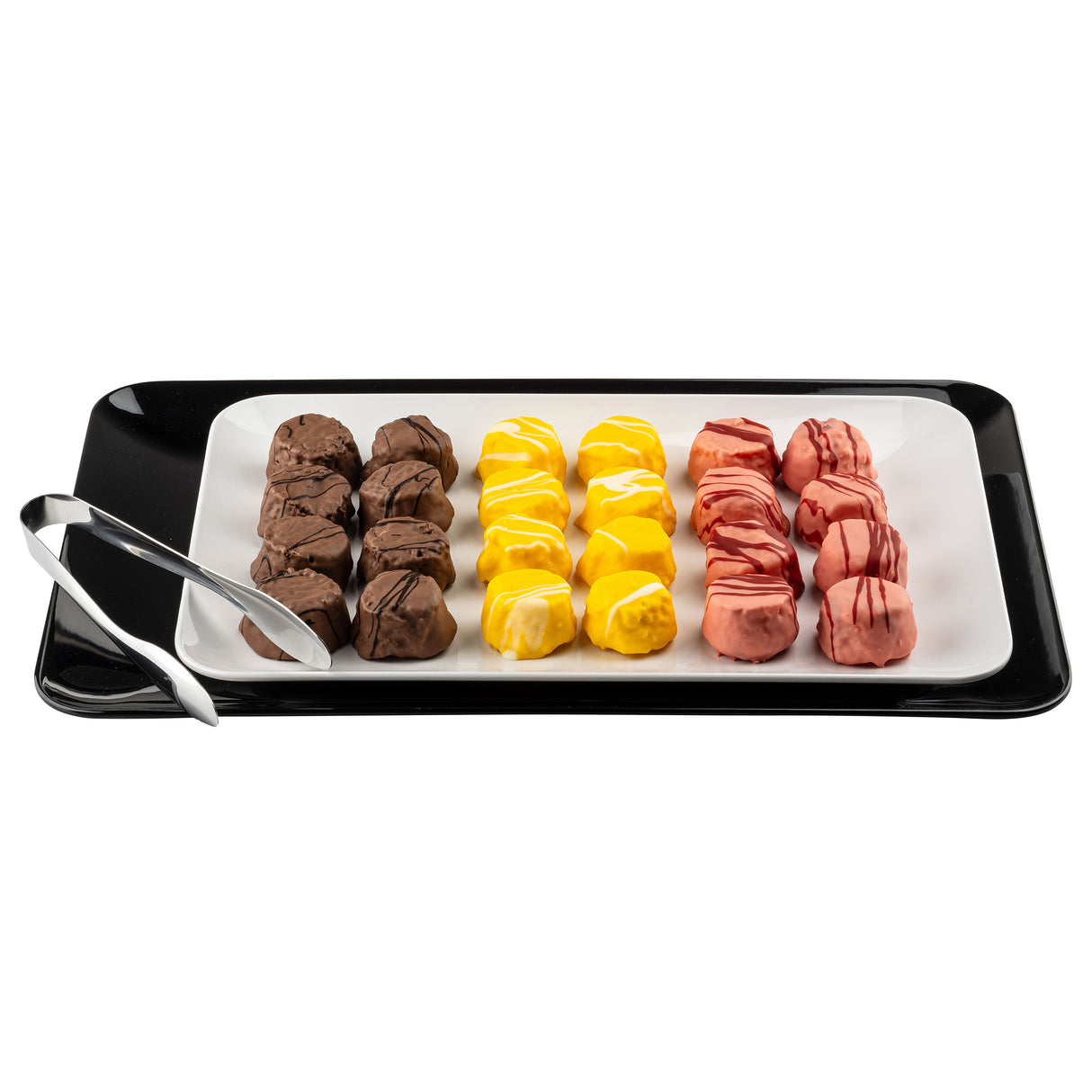 A black rectangular platter holds a white plate with three neat rows of colorful truffles: brown (left), yellow (center), and pink (right). Each row has five truffles, with silver tongs on the Sierra Collection serving platter’s edge. The background is white.