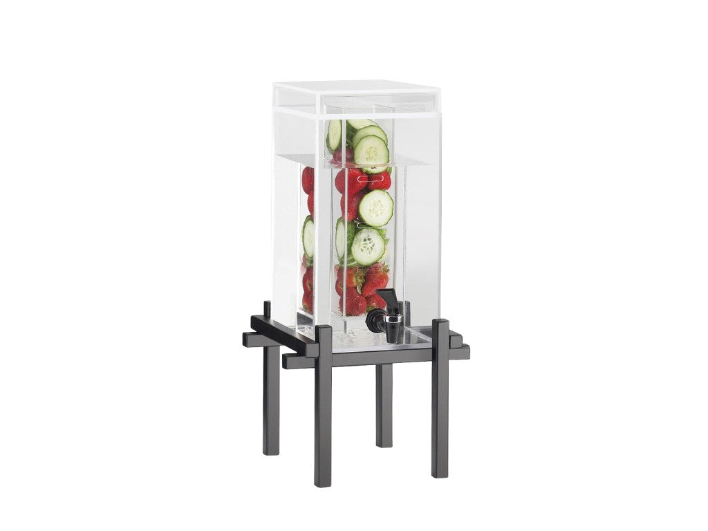 A tall, clear beverage dispenser with an infusion chamber rests on a black metal base, filled with water, vertically stacked cucumber and strawberry slices. A silver spigot at the bottom allows for easy pouring.