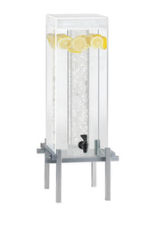 A tall, rectangular 5-gallon beverage dispenser filled with ice in its spacious ice chamber and garnished with lemon slices, stands elegantly on a modern silver metal base with a black spigot for easy drink dispensing.