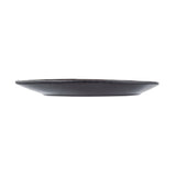 A black Lunara Collection Serving Plate by TableCraft Products is viewed from the side against a white background. The round, flat melamine serving plate features a thin, smooth rim and minimalist, modern design that highlights its low profile.