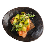 A slice of dark bread topped with smoked salmon, avocado slices, microgreens, and black pepper, served on a stylish Lunara Collection Serving Plate against a white background.