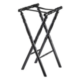 A black rubberwood folding luggage rack with a classic spindle design, featuring four turned legs, two crossed support straps on top, and decorative grooves along the legs. The rack stands open and upright on a white background.