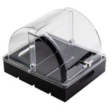 A rectangular black and clear acrylic display case with a domed, hinged lid and side handles resembles the TableCraft 11688 half-size polycarbonate cover. Silver tongs rest on one side of the tray. The empty case is shown on a white background.