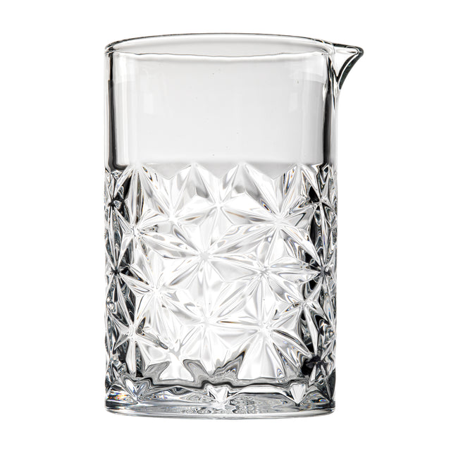 A clear TableCraft mixing glass from the Waverly Collection features geometric, starburst-patterned embossing on the lower half, a smooth upper section, and a small pouring spout. The pitcher stands upright against a white background.