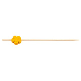 A natural bamboo pick with a small, orange, flower-shaped decoration near the blunt end. These decorative picks from TableCraft Products feature a pointed tip and are set against a plain white background.