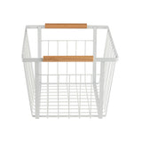 A white powder coated steel storage basket with two light wooden handles, shown from the front. The basket is rectangular with a grid pattern base and open vertical wires on the sides. Its simple, modern design stands out against the plain white background.