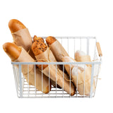 A white powder coated steel Storage Basket with wooden handles holds assorted baguettes and breadsticks wrapped in brown paper, each tied with string. The basket showcases various textures and colors of bread against a white background.
