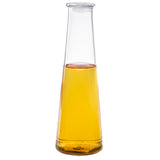 A TableCraft carafe filled with golden yellow liquid, likely oil or vinegar, sits against a plain white background. This clear 34 oz glass carafe has a wide base, tall narrow neck, and no visible cap. Light reflects off its smooth surface.