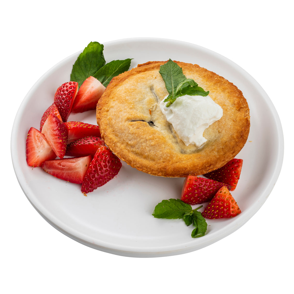 A golden-brown mini pie topped with whipped cream and a mint leaf sits on a Terra Collection serving plate, accompanied by sliced fresh strawberries and additional mint leaves, all set against a white background.