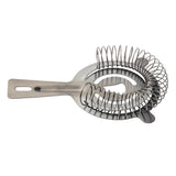A gunmetal stainless steel cocktail strainer with a coiled spring, flat handle with a hanging cutout, and prongs for stability, used to strain ice when pouring mixed drinks from a shaker. The background is white.
