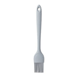 A gray silicone basting brush with flexible bristles and a long handle featuring a hole at the top for hanging, shown against a plain white background. This NSF-certified basting brush is both durable and easy to clean.