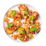 A white melamine serving plate from the Ridge Collection holds six pieces of bruschetta topped with diced tomatoes, onions, green bell peppers, and fresh basil—arranged in a circle. The background is white, highlighting the food’s fresh and colorful appeal.