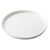 A plain, round white TableCraft Ridge Collection Serving Plate with slightly raised edges, photographed from a slight angle against a white background. The plate’s smooth, glossy surface features no visible patterns or decorations.