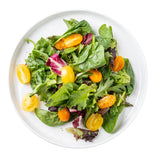 A white melamine serving plate from the Ridge Collection holds mixed leafy greens and halved yellow cherry tomatoes; the salad is fresh, lightly seasoned, and displayed on a white background.
