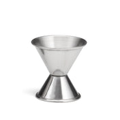 A stainless steel cocktail measuring jigger with two conical sections joined at the base, forming an hourglass shape. The top cone is larger, the bottom smaller. Used in bartending, its shiny surface reflects light beautifully.
