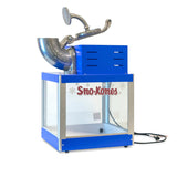 A blue and silver countertop Shav-A-Doo Sno-Kones ice shaver machine by Gold Medal Products, with a clear glass enclosure, metal handle, top chute for shaving ice or Sno pan, red Sno-Kones lettering with snowflakes, and a black power cord.