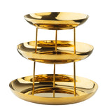 A three-tiered Seafood Tower with a gold finish and shiny, reflective surfaces. Each tier consists of a round, shallow dish supported by three vertical rods, forming an elegant and modern stainless steel centerpiece. The background is plain white.
