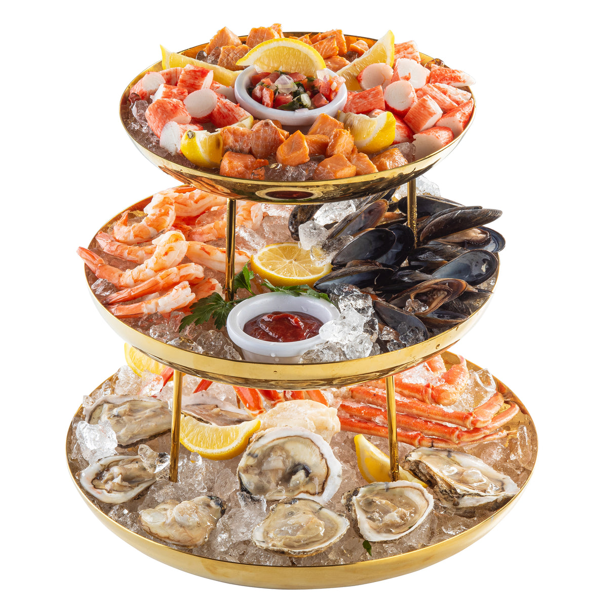 A three-tiered Seafood Tower holds oysters, shrimp, crab legs, mussels, scallops, and lobster on ice with lemon wedges. Cocktail sauce, ceviche, and a lemon half accompany the gold finish trays set against a white background.