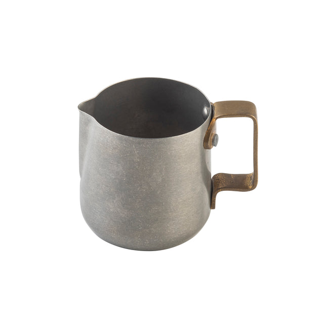 A small, metallic frothing cup with a matte gray finish and a wide brass handle. The pitcher, made from stainless steel, features a rounded body, a slight spout for pouring, and a simple, industrial design. The background is plain white.