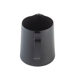 A matte black stainless steel frothing cup with a nonstick PTFE coating, featuring a wide opening, small pouring spout, and flat handle, shown from a high angle against a white background.