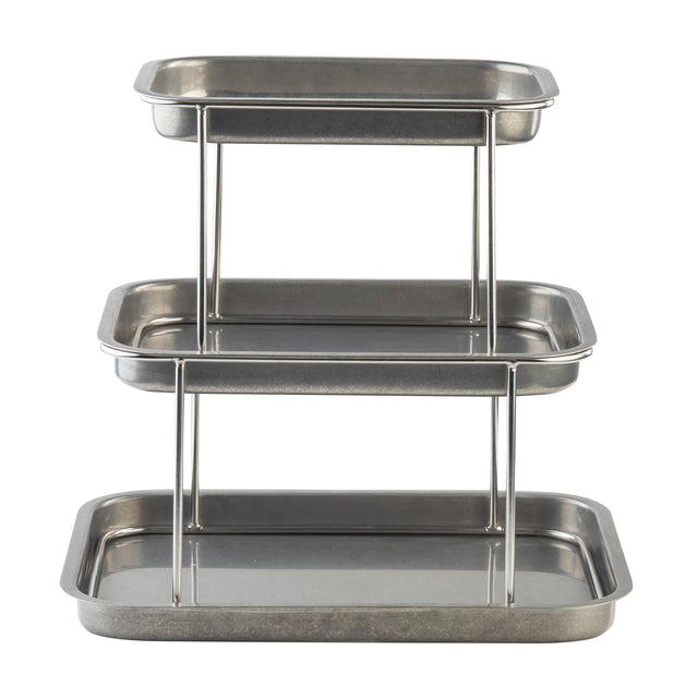 A 3-tier Sharing Tower with rectangular trays of decreasing size stacked vertically. Each tray is crafted from stainless steel with raised edges, supported by metal rods for a functional, industrial look. The empty trays reflect light beautifully.
