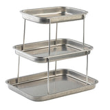 A 3-tier Sharing Tower features rectangular stainless steel trays stacked vertically, each with rounded edges and raised sides. Supported by four metal rods at each corner, the polished structure offers a sleek, modern look for serving.
