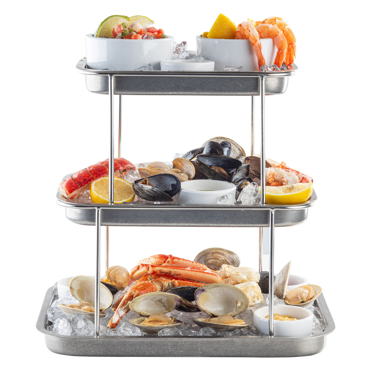 A 3-tier stainless steel Sharing Tower on ice displays cocktail shrimp with lemon, oysters, mussels, lobster tail, clams, crab legs, and dipping sauces. The seafood is neatly arranged with lemon wedges and small bowls of sauce on each tier.