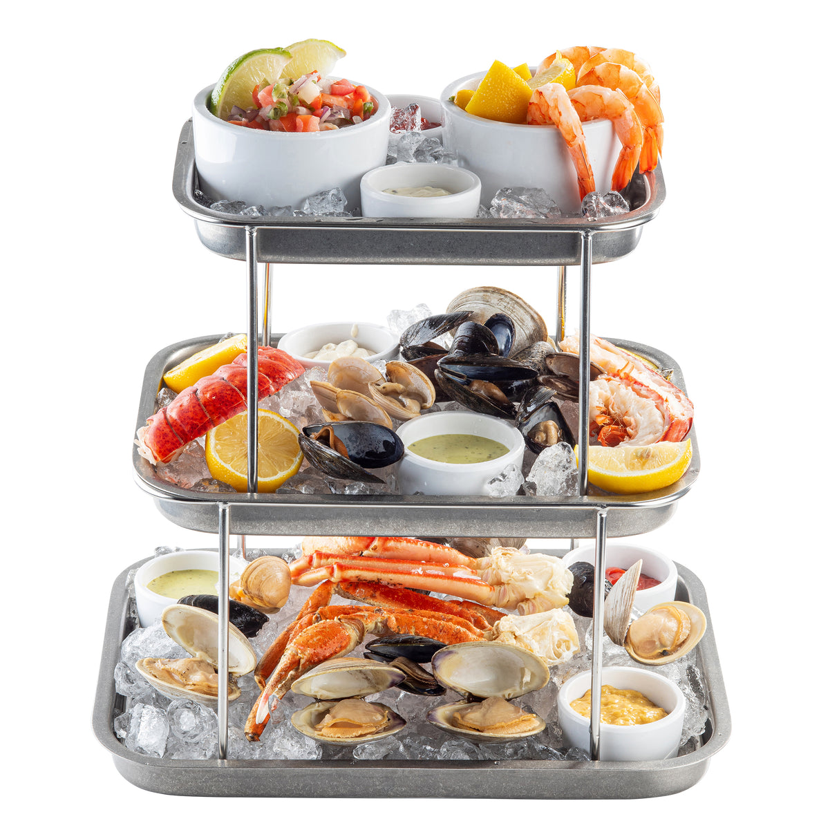 A three-tier Sharing Tower on stainless steel trays showcases shrimp, crab legs, lobster, oysters, clams, mussels, lemon wedges, dipping sauces, and ceviche with tortilla chips—all fresh and colorful for the perfect seafood experience.