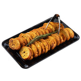 A black rectangular TableCraft serving platter holds neatly arranged golden-brown toasted baguette slices. A sprig of rosemary lies on top, and metal tongs rest at one end. The background is plain white.