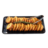 A black TableCraft melamine serving platter holds neatly arranged slices of toasted baguette, garnished with a sprig of rosemary in the center. Metal tongs rest on one side of the tray against a plain white background.