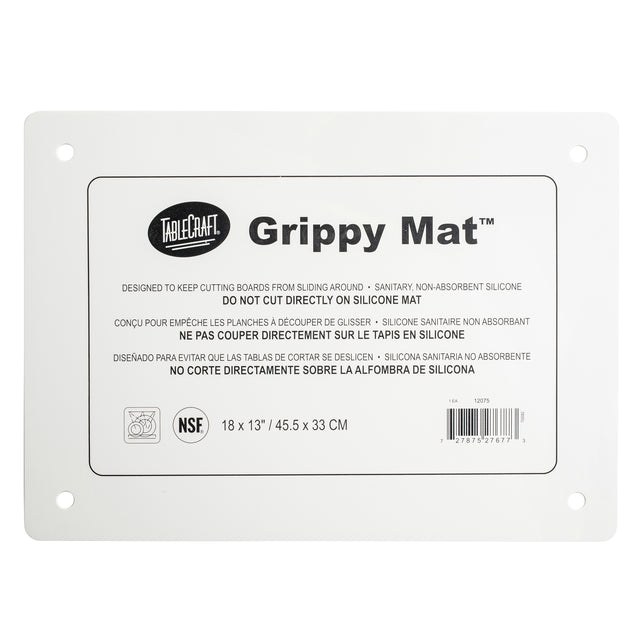 A rectangular white Grippy Mat Cutting Board by TableCraft. This anti-slip cutting mat features rounded corners, four corner holes, and a multilingual label with use and care instructions. Size: 18x13 in (45.5x33 cm).