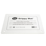 A white rectangular NSF cutting board labeled Grippy Mat Cutting Board by TableCraft, 18 x 13 inches, with rounded corners and four holes. This anti-slip cutting mat displays instructions and warnings in English, French, Spanish, plus an NSF logo and barcode.