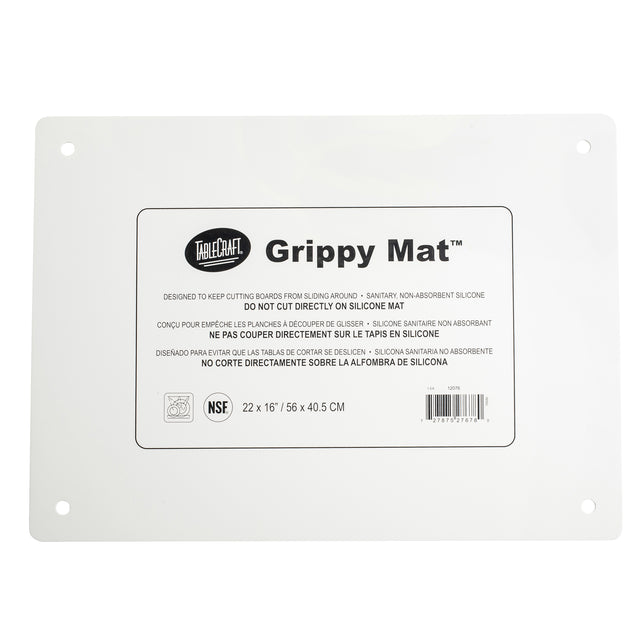 A rectangular white silicone imprinted mat with rounded corners and four holes, one near each corner. The center label reads “TableCraft Grippy Mat” with usage instructions and dimensions: 22 x 16 inches—an ideal anti-slip cutting board mat.