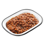 A white, oval-shaped enamel serving pan with a black rim is filled with baked beans in a rich, brown sauce. The beans are closely packed and glistening, with some sauce pooled around them for a hearty, comforting look from the Canteen Collection.