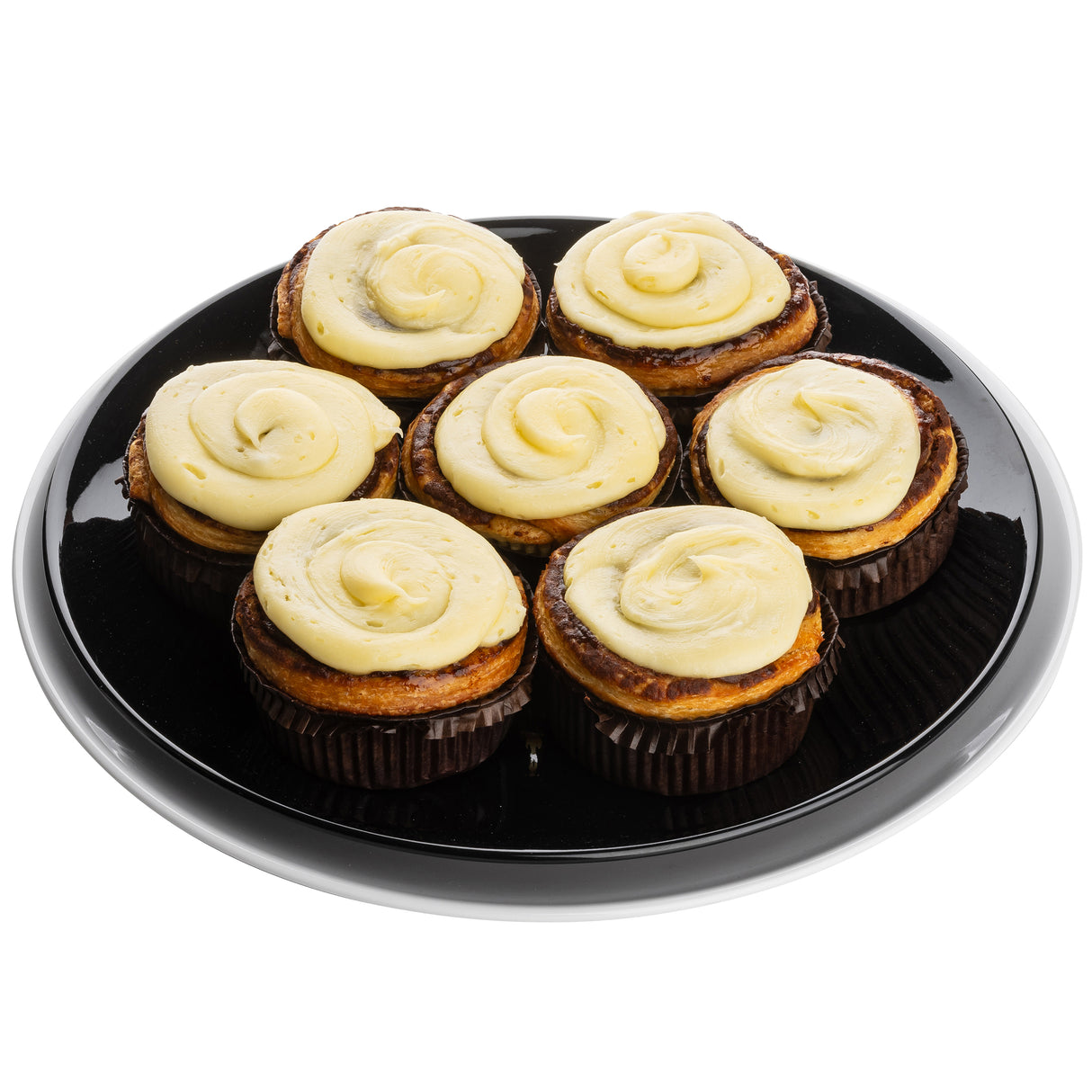 Seven cinnamon rolls topped with swirls of cream cheese frosting are arranged in a circular pattern on a shiny Sierra Collection Serving Platter by TableCraft Products, viewed from above against a white background. The golden brown rolls sit in dark paper wrappers.