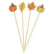 Four wooden cocktail picks, perfect as Decorative Picks, are topped with autumn-themed accents: an orange pumpkin, fall leaves picks, and a striped yellow pumpkin—all arranged in a fan shape against a white background.